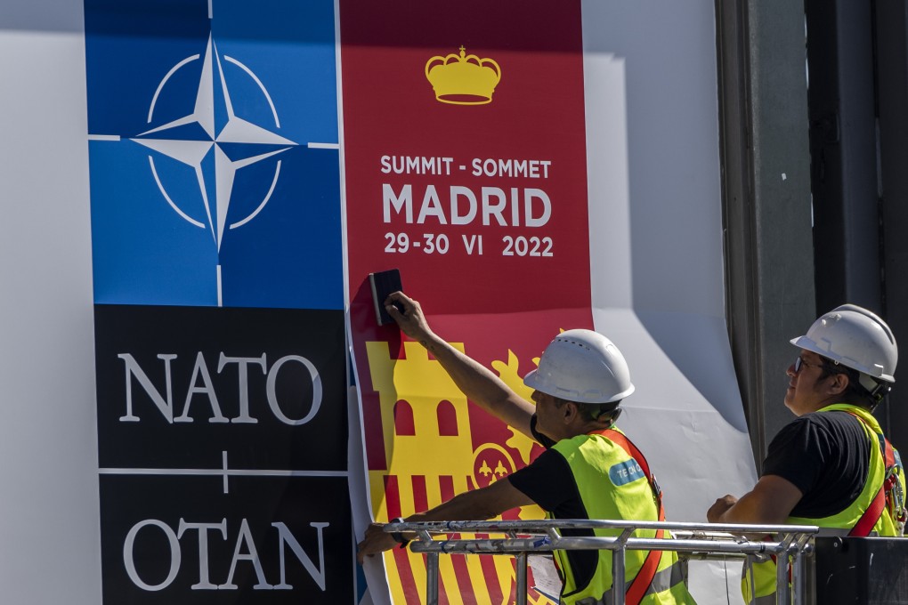 A worker fixes a Nato poster outside the summit building in Madrid on June 27. Photo: AP