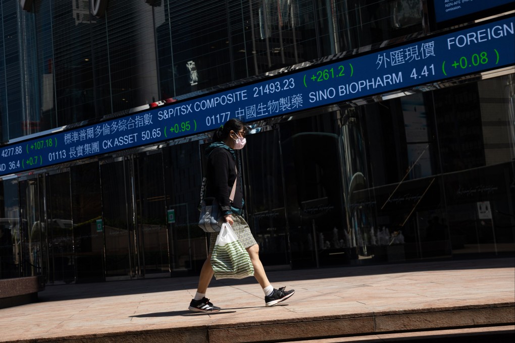 A woman walks past an electronic stock market ticker near the Exchange Square in Cenral, Hong Kong. Photo: EPA-EFE