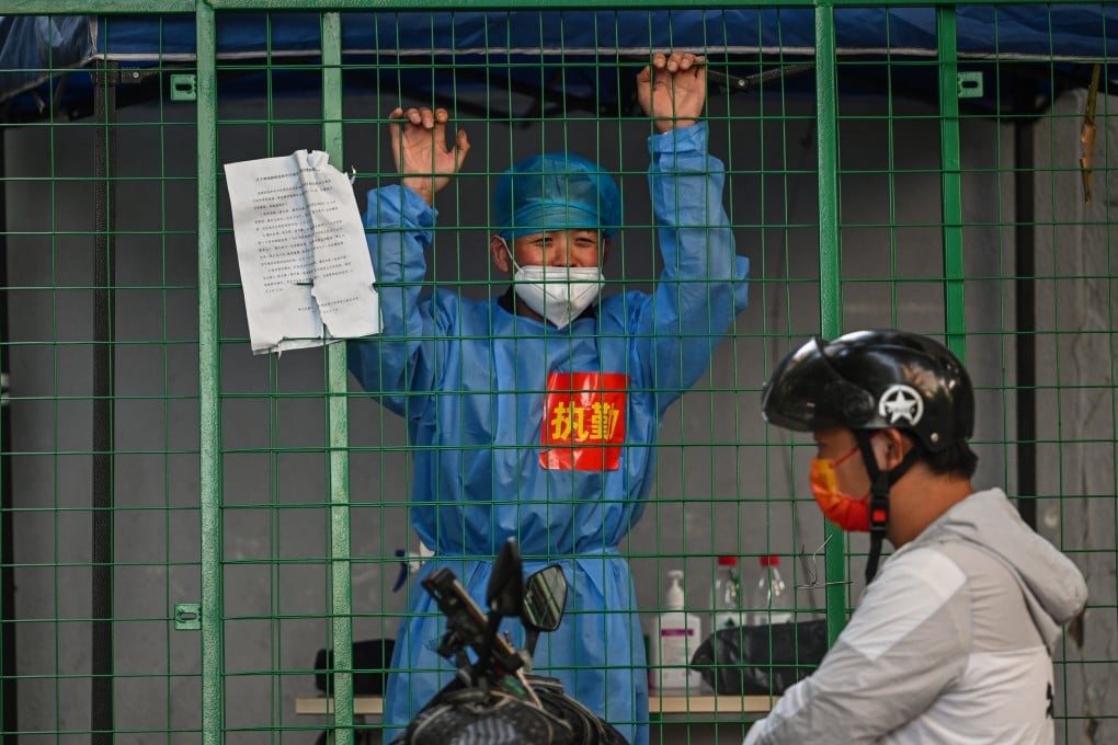 A medical worker in a residential area under Covid-19 lockdown talks with a man on a scooter in the Xuhui district of Shanghai, China, on June 16, 2022. Photo: AFP