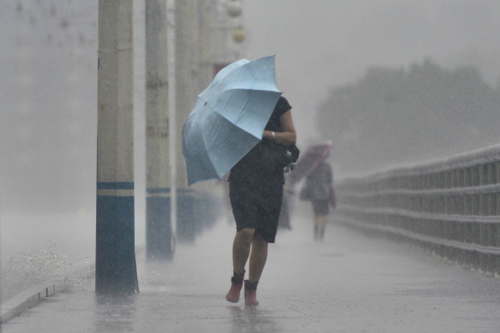 People walk in heavy rain in Pyongyang, North Korea, on Tuesday. Photo: Kyodo