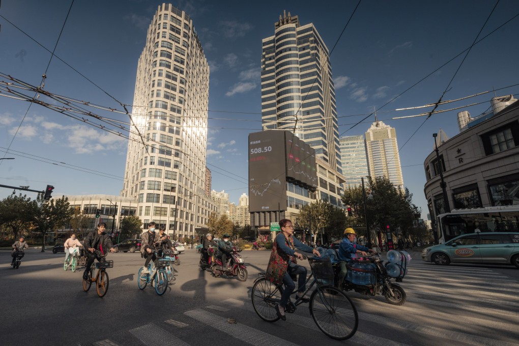 People ride bicycles on the street next to the large screen showing the stock exchange data in Shanghai in November 2021. Photo: EPA-EFE