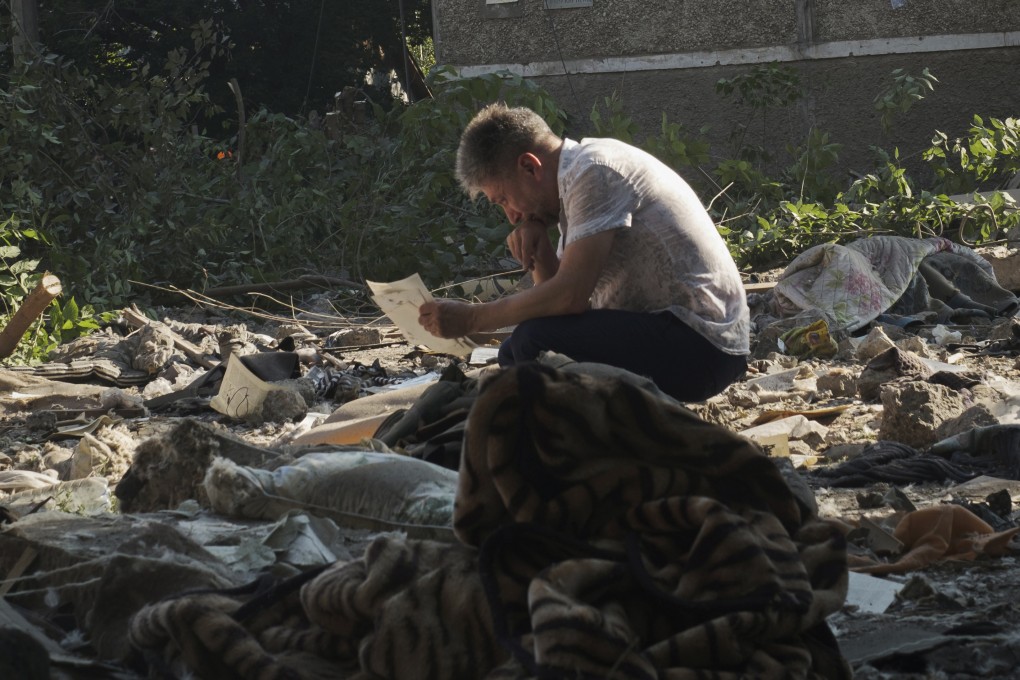 A local resident collects family photos from under the rubble after Russian shelling in Mykolaiv, Ukraine, this week. Photo: AP