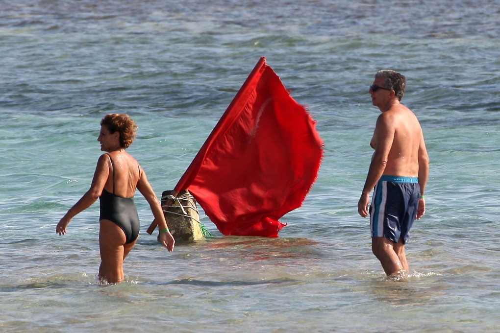 Tourists walk past a red flag serving as a warning of shark sightings on a beach in Egypt’s Red Sea resort of Sharm el-Sheik. Photo: AFP