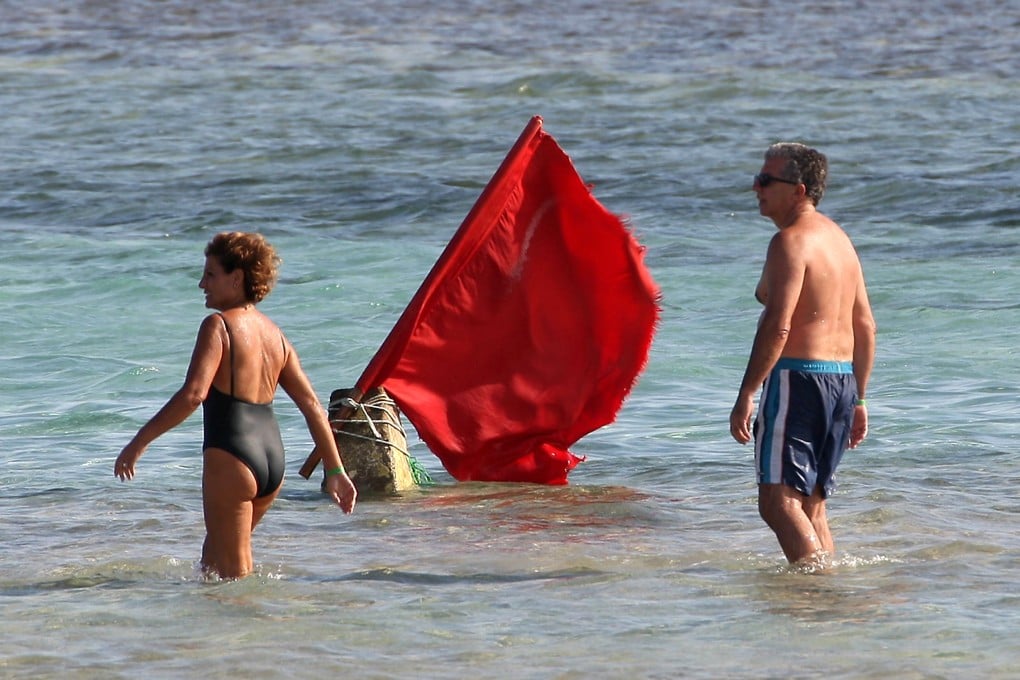 Tourists walk past a red flag serving as a warning of shark sightings on a beach in Egypt’s Red Sea resort of Sharm el-Sheik. Photo: AFP