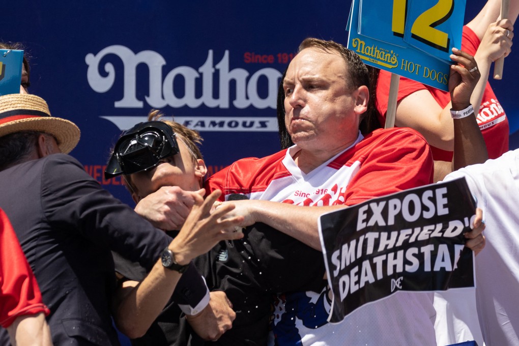 Joey Chestnut tackles a protester who interrupted the Nathan’s Famous Fourth of July hot dog eating contest on Monday. Photo: AFP