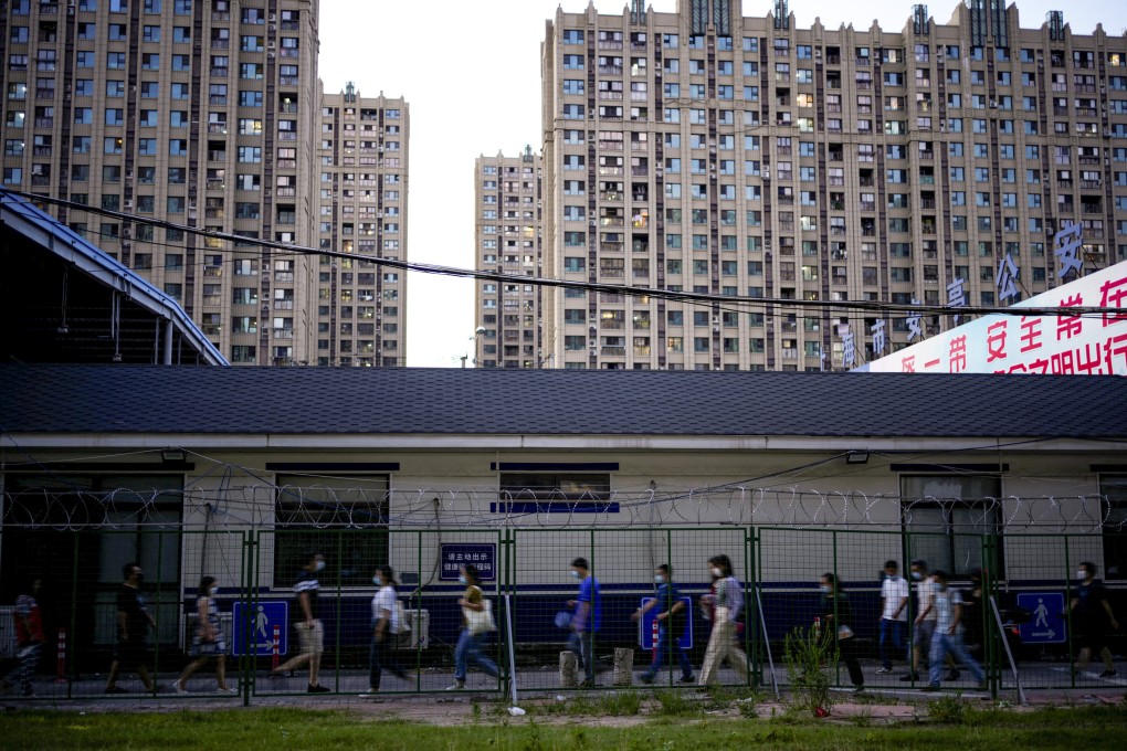 People, wearing a face mask following the coronavirus outbreak, walk past a barrier on a street in Shanghai on July 1. Photo: Reuters