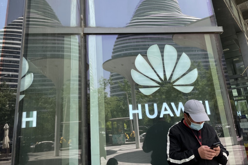 A man reads from his mobile phone in front of Huawei’s logo in Beijing on April 27. Photo: Simon Song