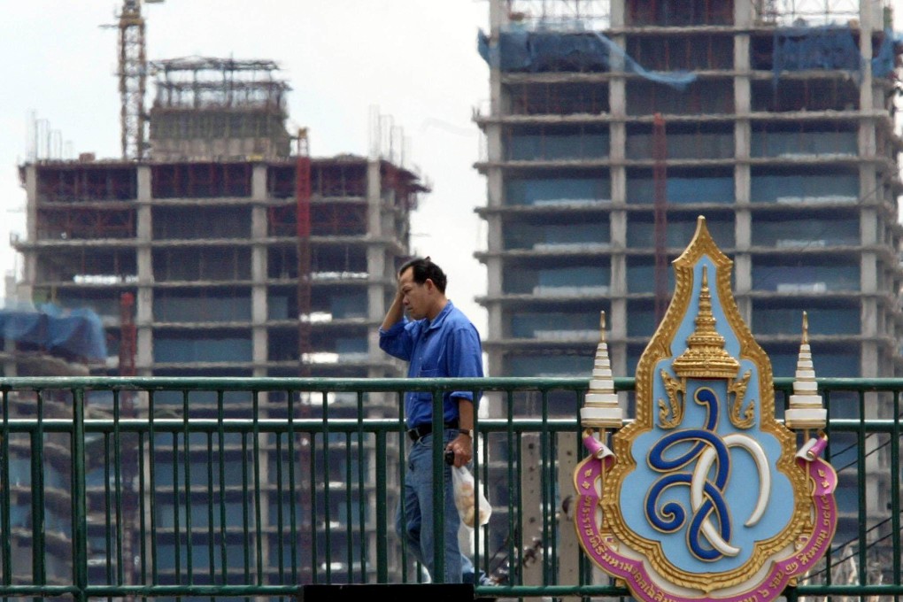 A man walks past two among the hundreds of unfinished buildings which were abandoned mid-construction during the Asian financial crisis, in Bangkok in August 2004. The devaluation of the Thai baht in July 1997 sparked a drop in currencies around the region. Photo AFP