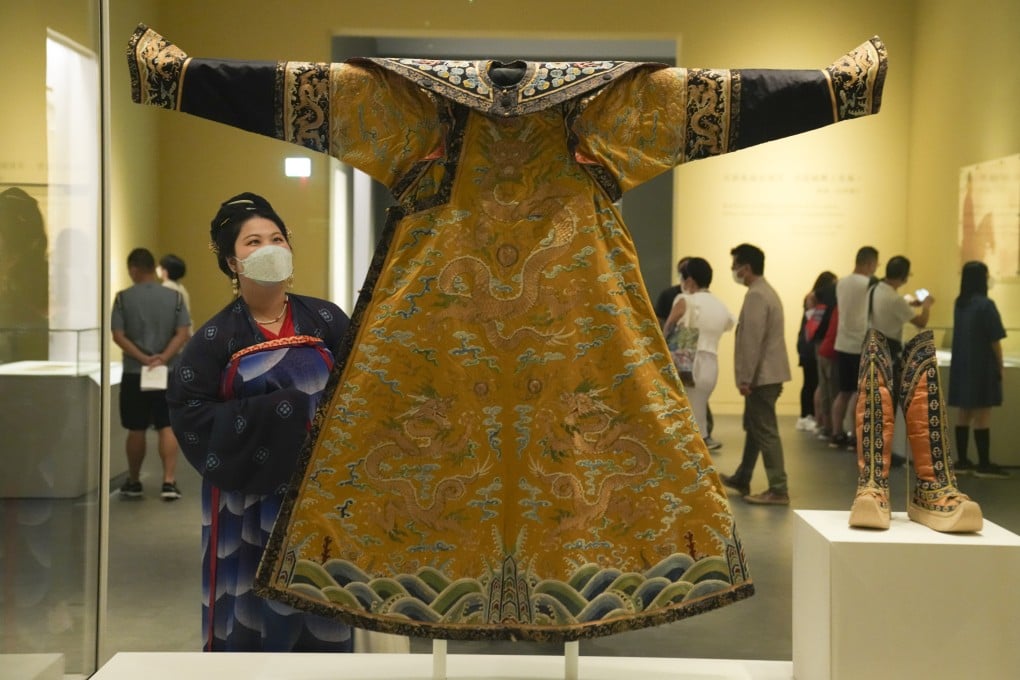 A woman dressed in traditional clothing admires a festive robe once worn by an emperor at the Hong Kong Palace Museum. Photo: SCMP