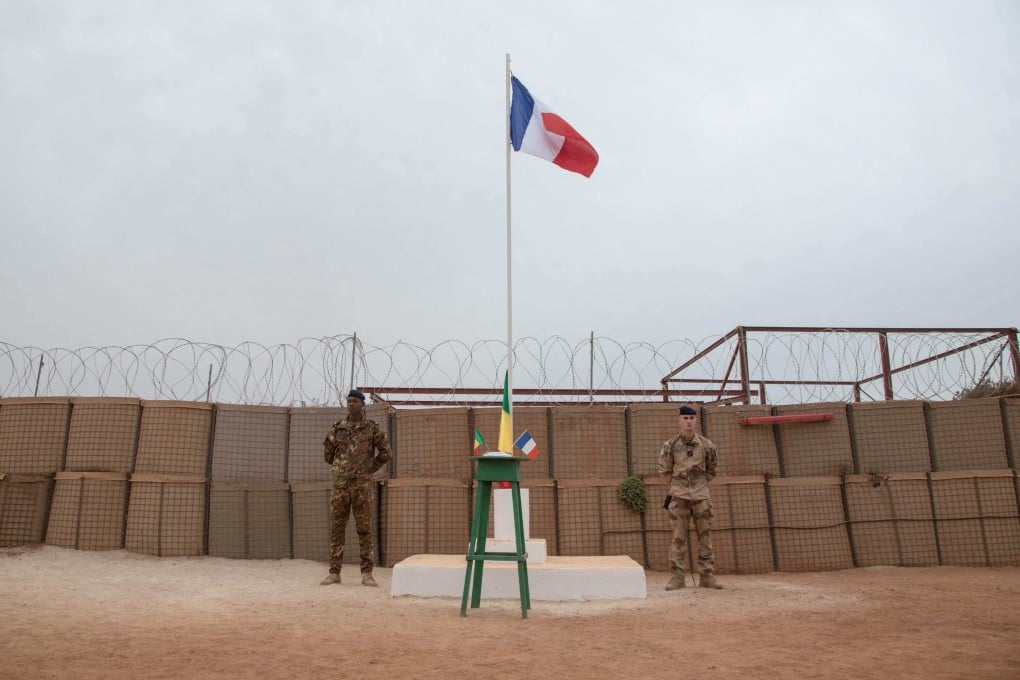 A Malian and a French soldier stand on either side of the Barkhane camp flagpole before the handover ceremony of the Barkhane military base to the Malian army in Timbuktu in December. Photo: AFP