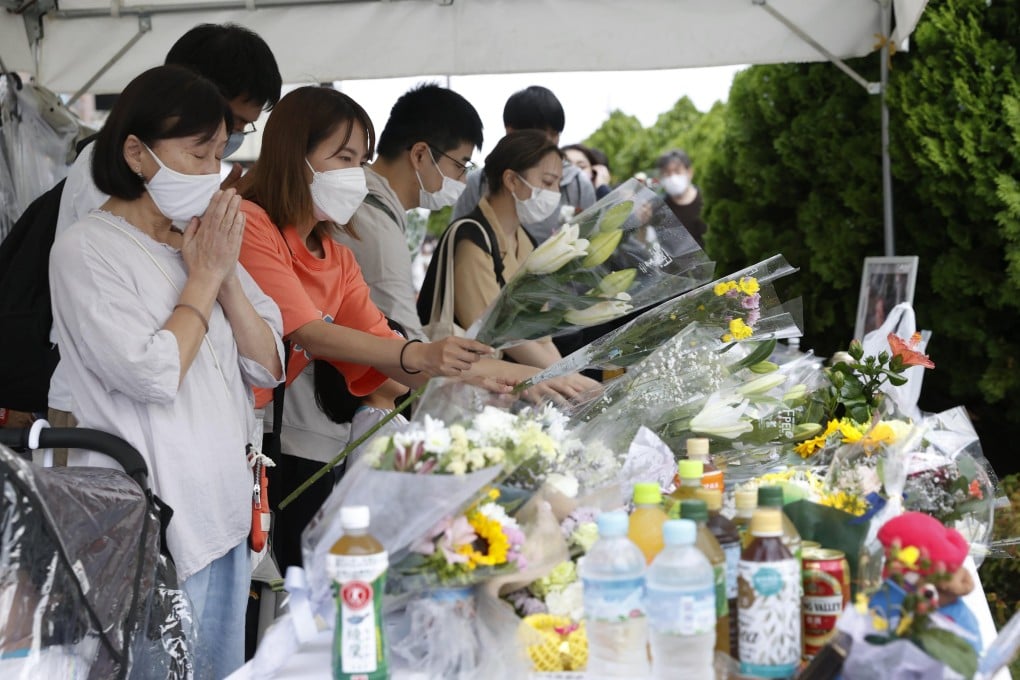 People offer prayers near the site of Shinzo Abe’s shooting. Photo: Kyodo News via AP