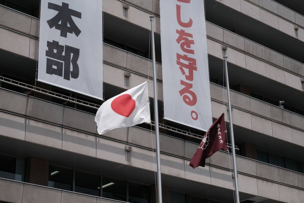 A Japanese national flag, left, and Liberal Democratic Party (LDP) flag fly at half-mast on Monday at the party’s headquarters in Tokyo. Photo: Bloomberg