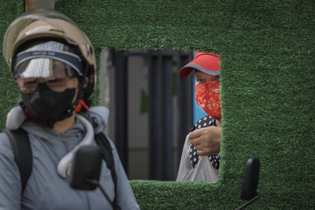 A woman takes food through an opening in a quarantine barrier in Shanghai, China. Photo: EPA-EFE