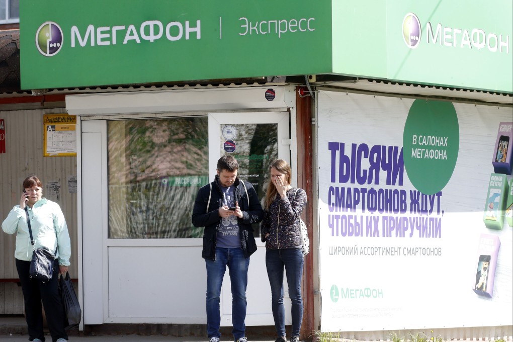 People use their mobile phones in front of a local office of MegaFon. Photo: EPA