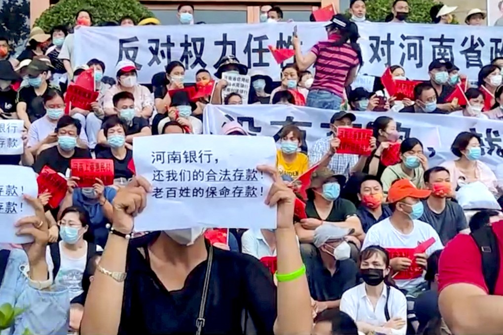 On Sunday, July 10, demonstrators hold up signs protesting against the freezing of deposits by some rural-based banks, outside a People’s Bank of China building in Zhengzhou, Henan province. The text in the foreground reads, “Henan Bank, return to us our legal deposits! The people’s life-saving deposits!” Photo: Reuters