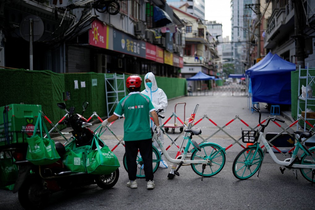 A worker in a protective suit gets food from a delivery worker at a closed residential area during lockdown, amid the Covid-19 outbreak in Shanghai, on May 25, 2022. Photo: Reuters