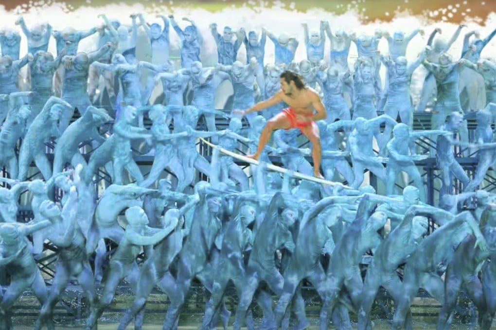 A still from “The People Make the Destination”, a tourism promotion video, features a surfer riding his board across “waves” of blue-clad dancers. Photo: Tourism Philippines