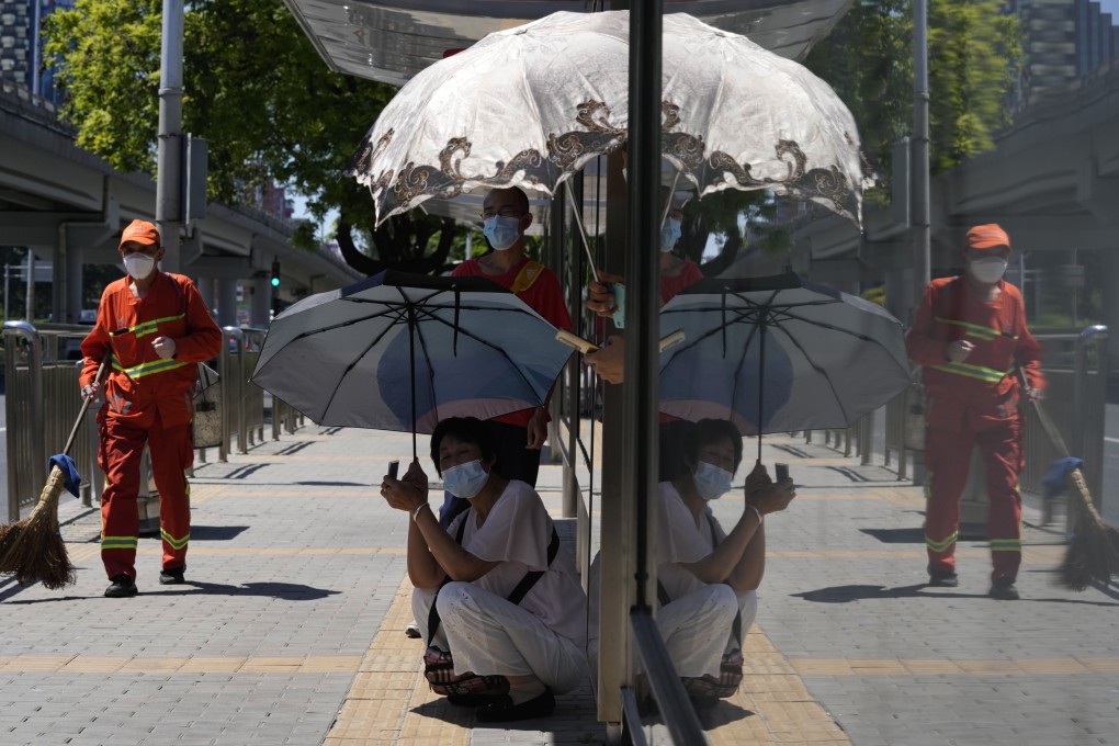 Residents take shelter from the sun as they wait for a bus in Beijing on July 15. Temperatures have surpassed all-time records as a heatwave sweeps across much of the country. Photo: AP