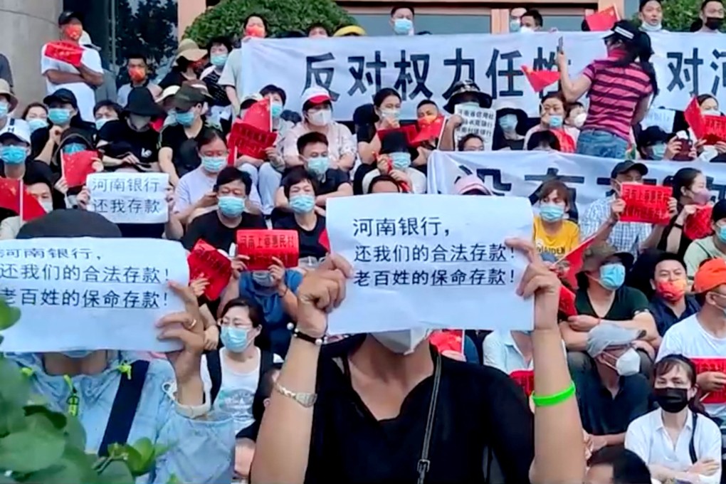 Demonstrators hold up signs during a protest over the freezing of deposits by some rural-based banks, outside a People’s Bank of China building in Zhengzhou, Henan province, China, on July 10. Photo: Reuters TV via Reuters