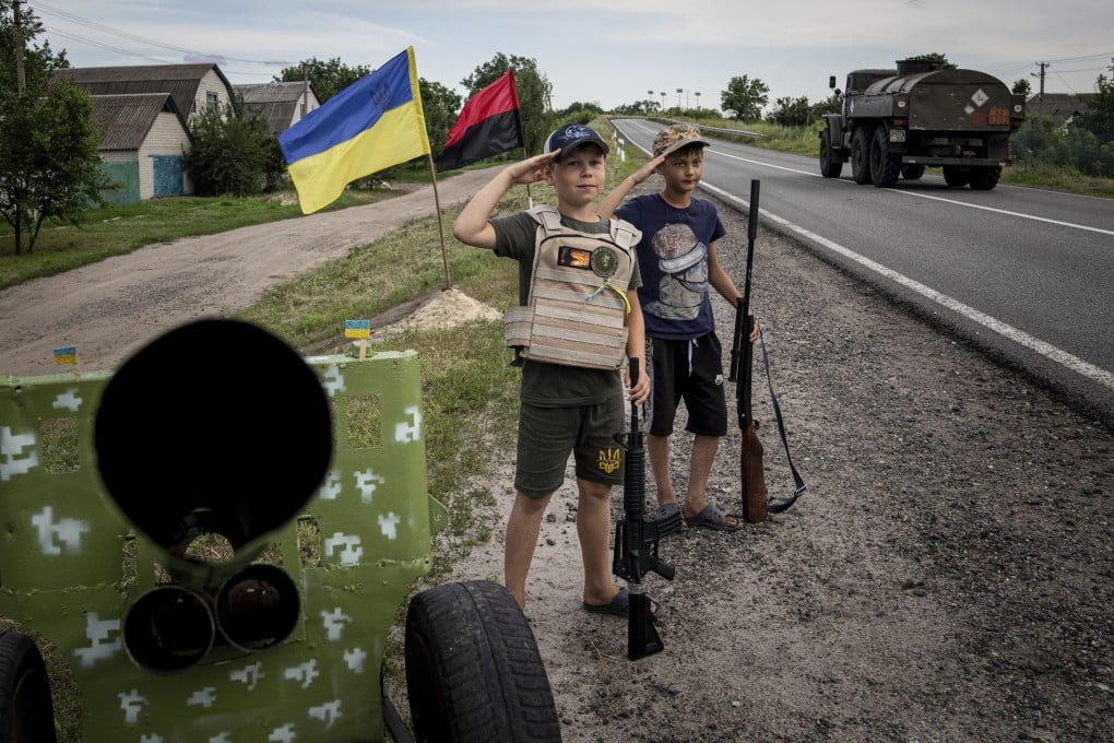Two boys with plastic guns salute Ukrainian soldiers at their self-made checkpoint on a highway in Kharkiv region, Ukraine. Photo: AP