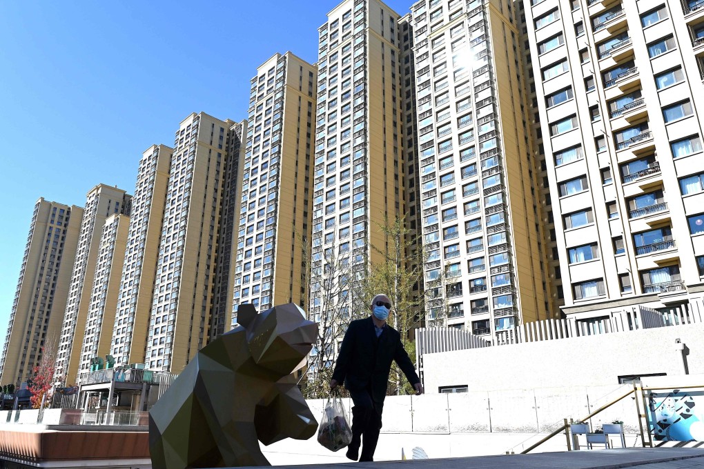 A man walks in front of a housing complex by Chinese property developer Evergrande in Beijing. The company faces a mortgage boycott crisis across the mainland. Photo: AFP