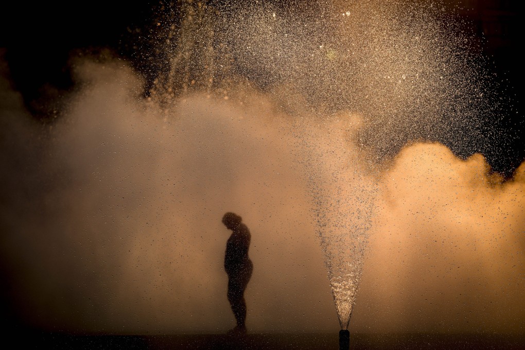 A woman cools off near a city fountain at sunset in Bucharest, Romania, amid a severe heatwave in July, 2022. Photo: AP