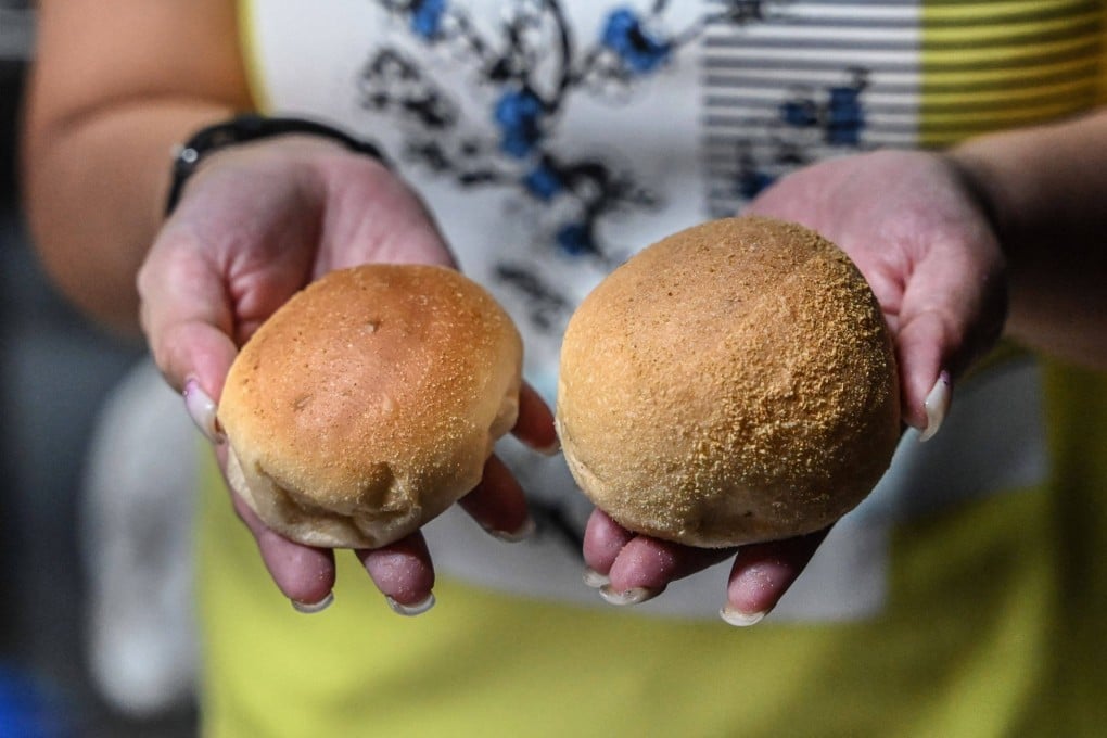 A staff member compares the sizes of the popular breakfast roll ‘pandesal’ at a bakery in Manila. Photo: AFP