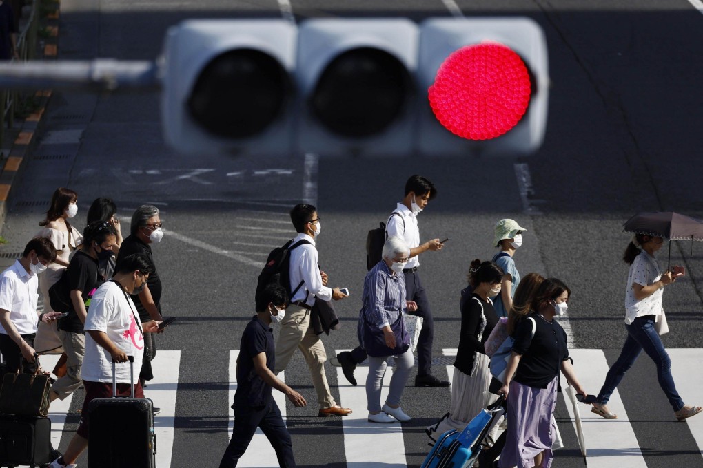 People wear face masks for protection against the coronavirus walk on a pedestrian crossing in Tokyo. Japan set a national record of more than 200,000 coronavirus cases on Saturday. Photo: Kyodo