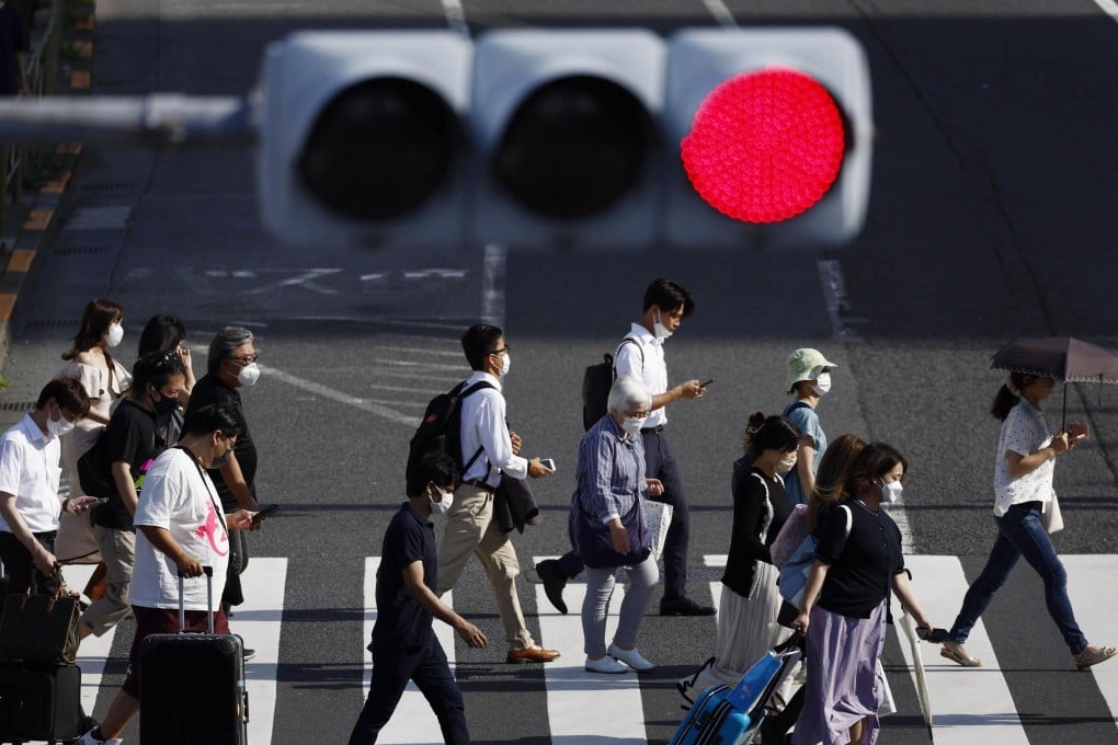 People wear face masks for protection against the coronavirus walk on a pedestrian crossing in Tokyo. Japan set a national record of more than 200,000 coronavirus cases on Saturday. Photo: Kyodo