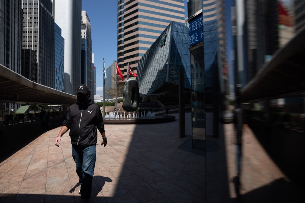 A man walks past an electronic board displaying the Hang Seng Index in March 2022. Photo: EPA-EFE