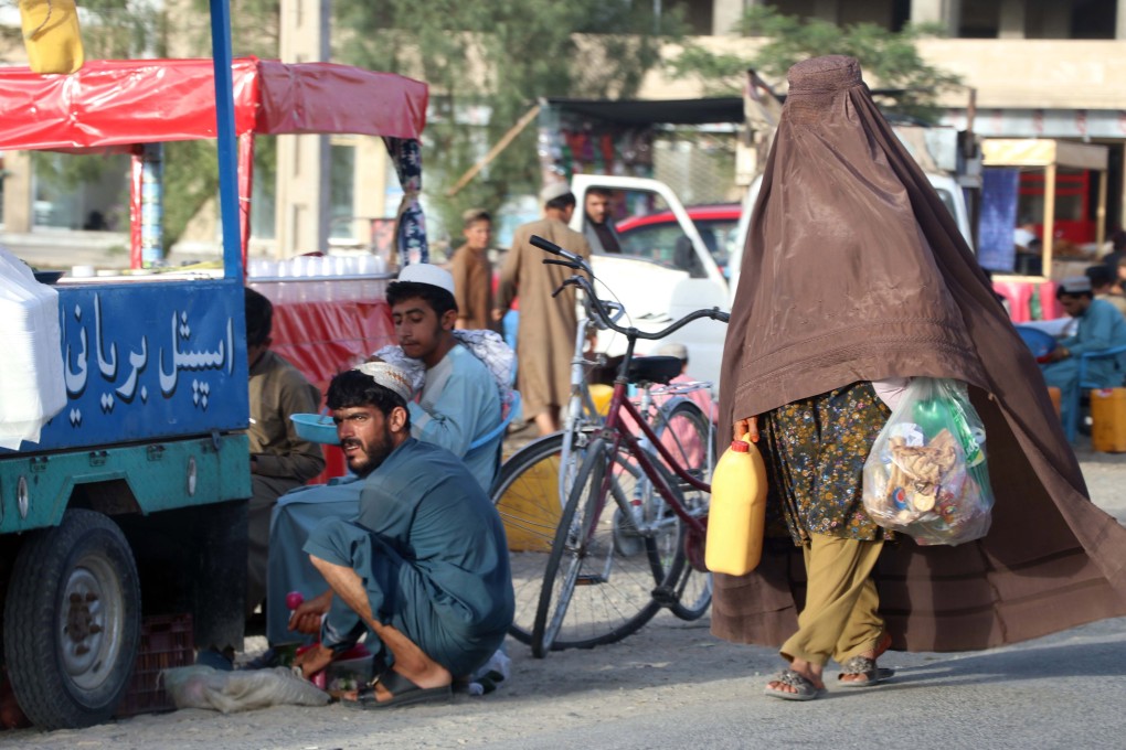 A burqa-clad Afghan woman walks past a roadside food vendor in Kandahar this month. Photo: EPA-EFE