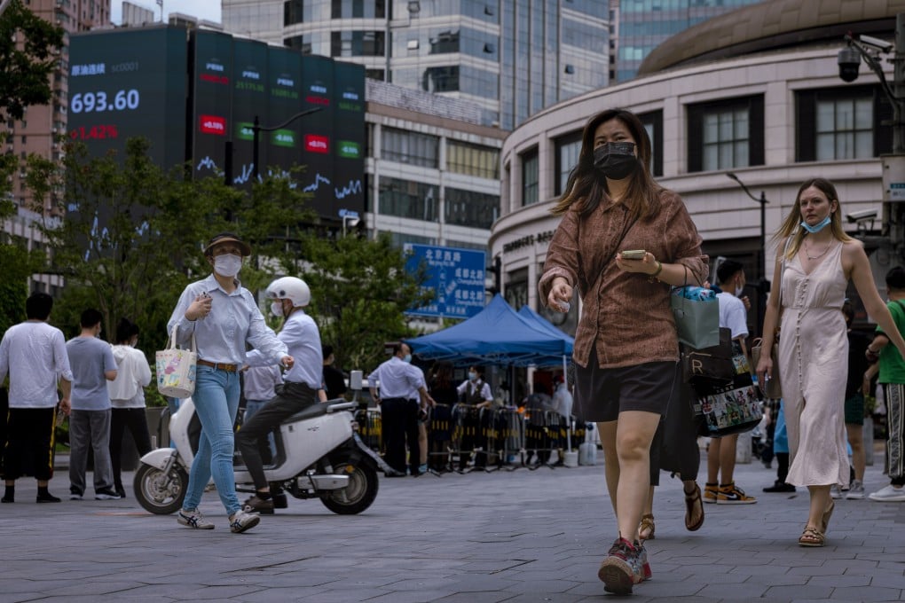 People walk past a giant screen showing economic and stock exchange updates, in Shanghai on June 23. Photo: EPA-EFE