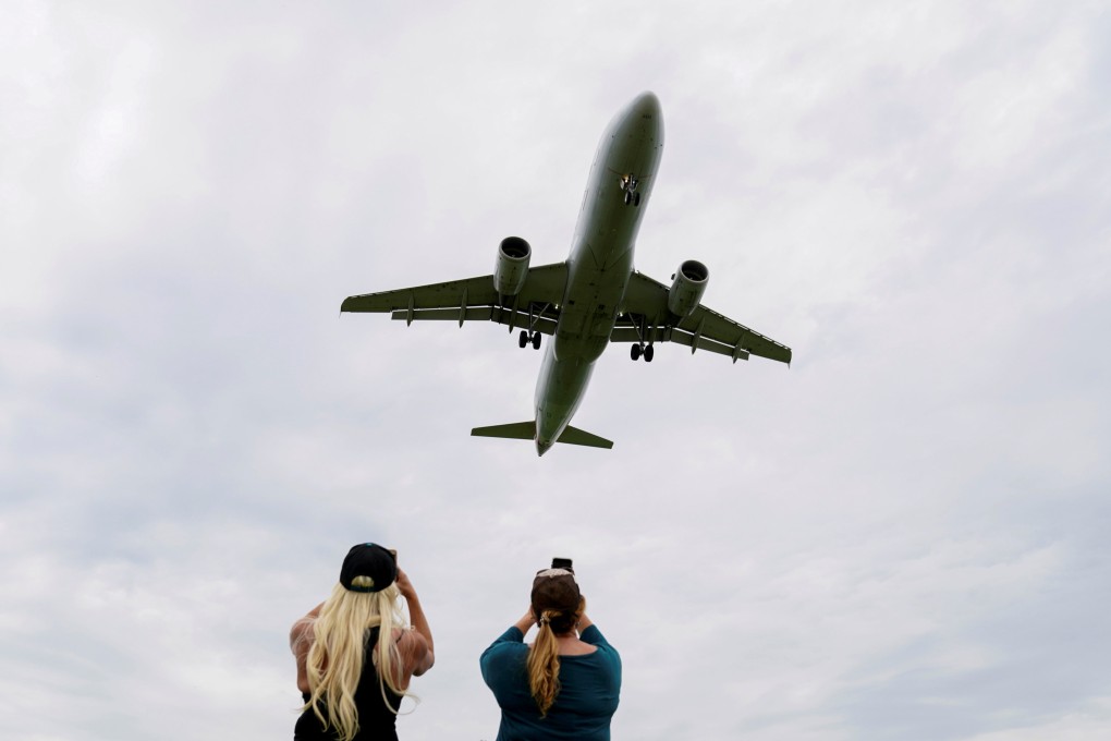 Women photograph a plane landing at an airport in Washington in April 2020. Photo: Reuters