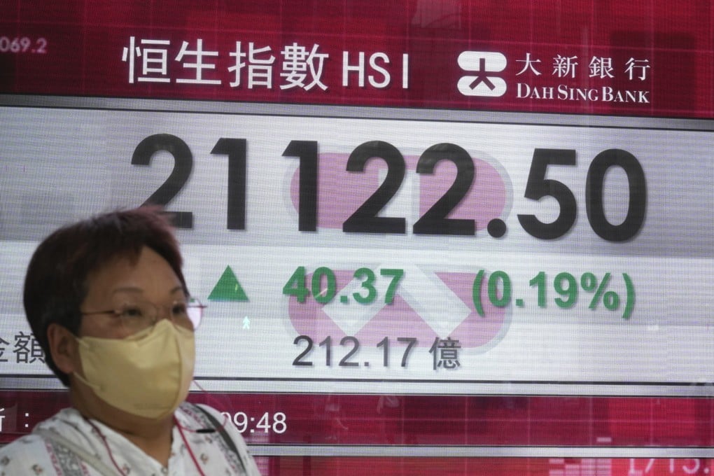 A woman walks past a bank’s electronic board showing the Hang Seng Index on June 6. Photo: AP