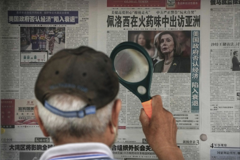 A man uses a magnifying glass to read a newspaper headline about US House Speaker Nancy Pelosi’s Asia visit, at a stand in Beijing on July 31. Pelosi’s possible stop in Taiwan has fuelled tensions with Beijing. Photo: AP