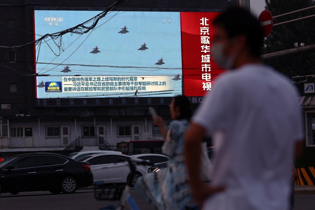 Pedestrians wait at an intersection near a screen showing footage of Chinese People’s Liberation Army (PLA) aircraft during an evening news programme in Beijing on Tuesday. Photo: Reuters