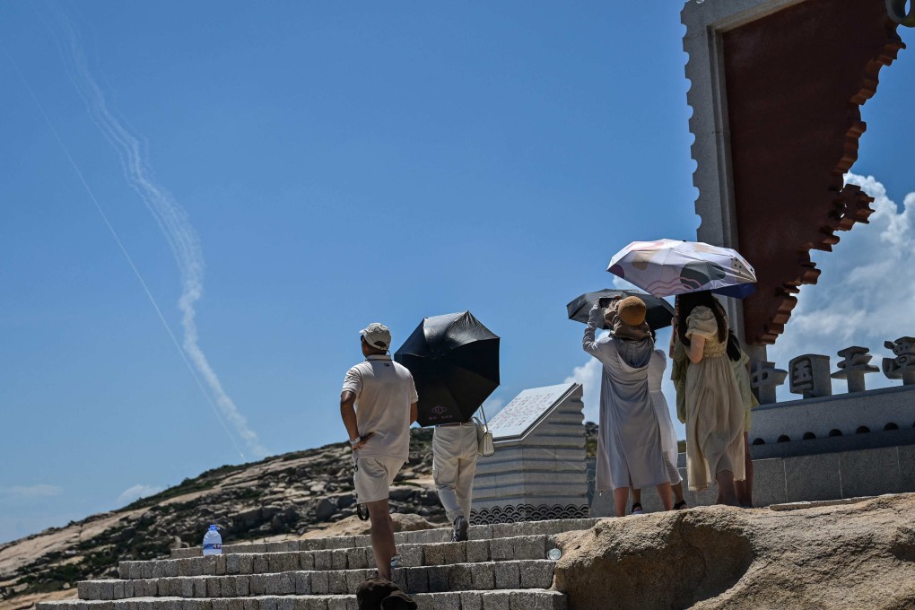 Tourists on Pingtan Island take in smoke trails from projectiles launched by the PLA on Thursday. Photo: AFP