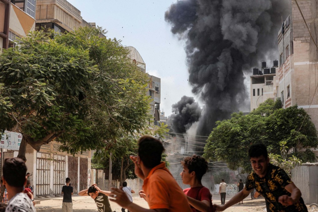People run for cover during an Israeli aerial bombardment in Gaza City. Photo: AFP
