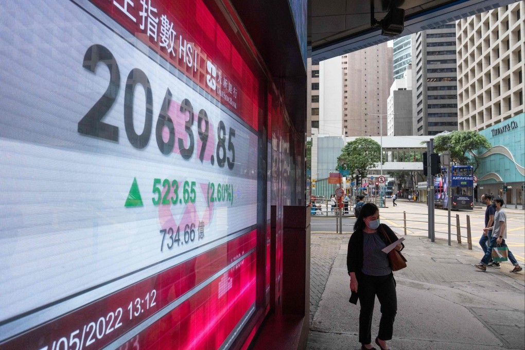 A woman walks past an electronic display showing the Hang Seng Index in the Central district of Hong Kong on May 27, 2022. Photo: AFP