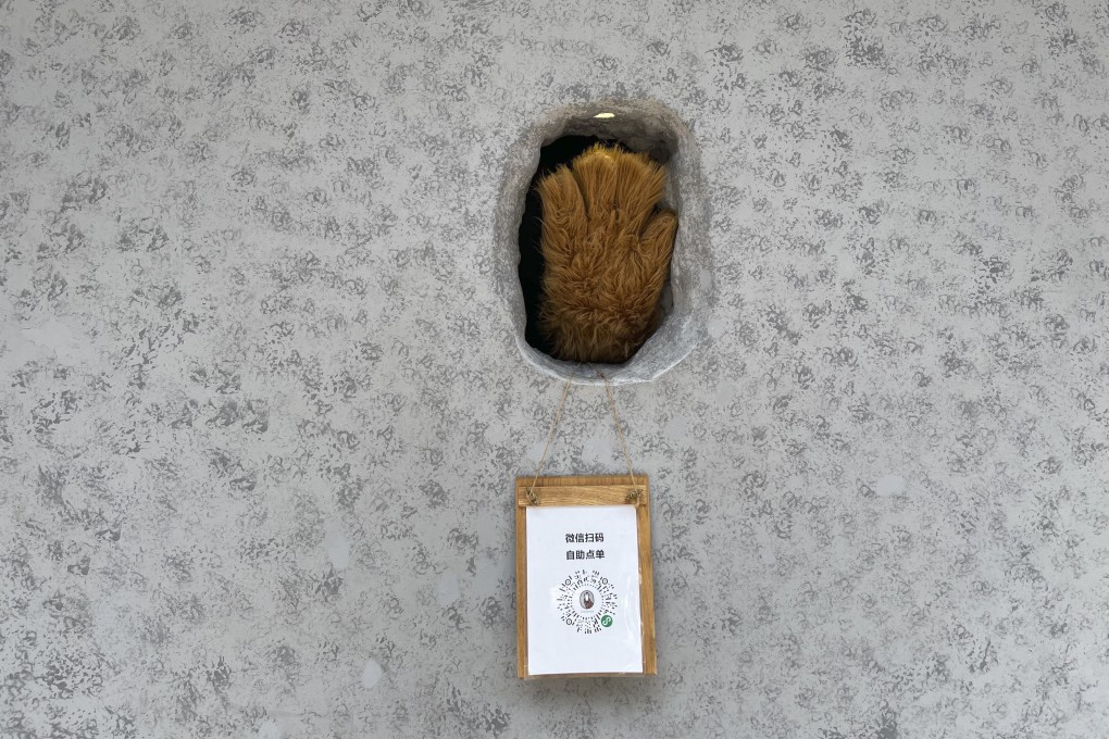 A barista waves out of a ‘hole-in-the-wall’ cafe in Shanghai. Photo: SCMP