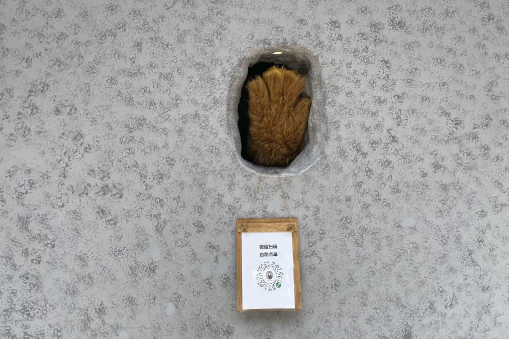 A barista waves out of a ‘hole-in-the-wall’ cafe in Shanghai. Photo: SCMP