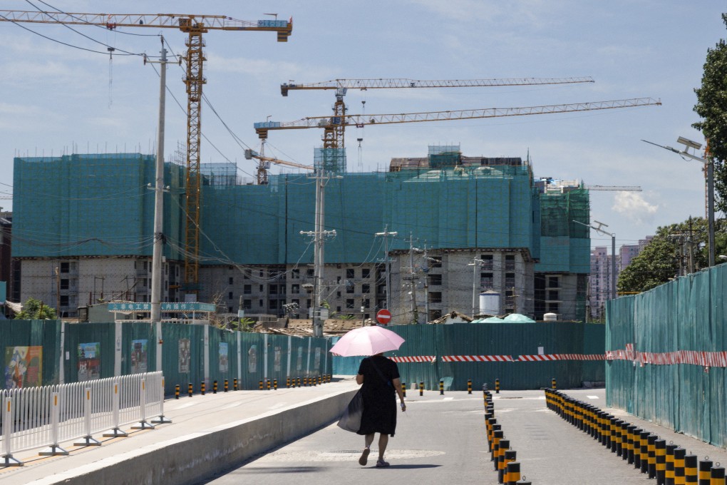 A woman walks near a construction site of apartment buildings in Beijing. Photo: Reuters