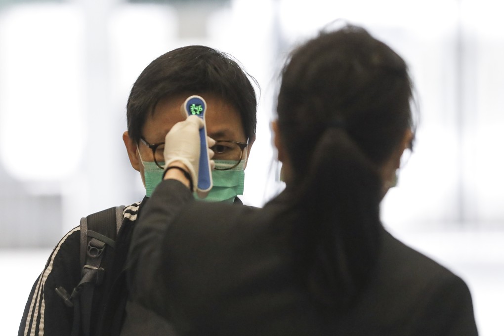 A security guard checks the temperature of a man before he enters a government building on March 2. Photo: Sam Tsang