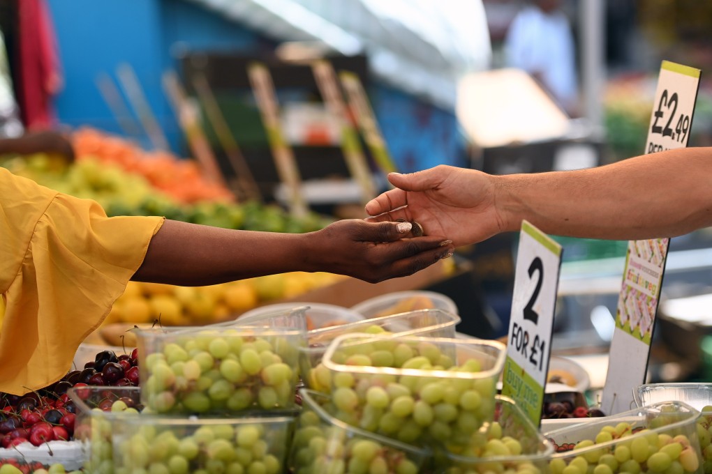 A customer pays for fruit at a market in London on July 20. With UK inflation hitting a 40-year high, the Bank of England raised interest rates. Photo: EPA-EFE