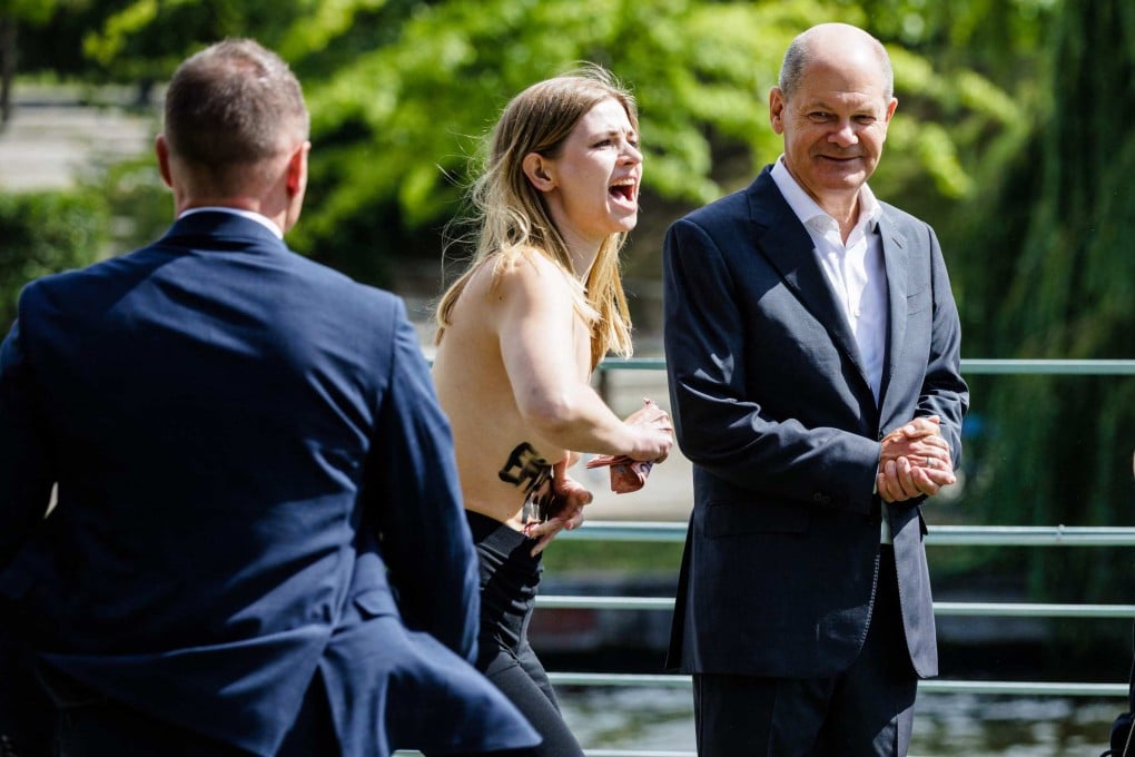 A topless protester, calling for an embargo on Germany’s import of Russian gas, beside German Chancellor Olaf Scholz during the Federal Government’s Open Day in Berlin, Germany on Sunday. Photo: AFP