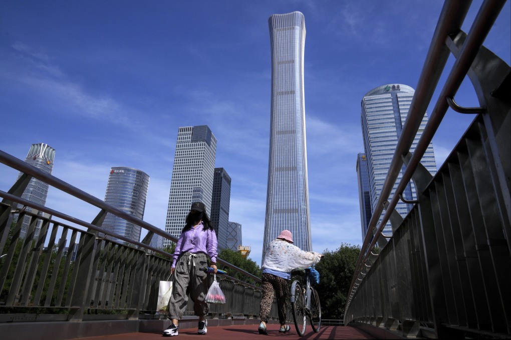 Residents walk on a pedestrian bridge against the office buildings in Beijing on August 22. Photo: AP