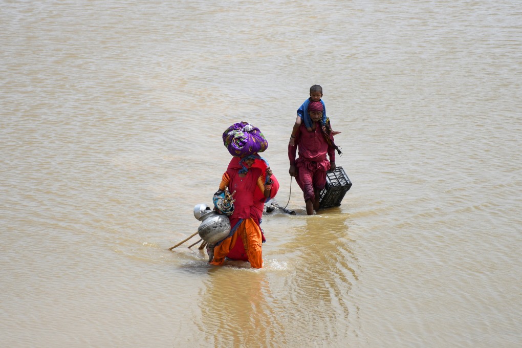 A family with their belongings wade through rain waters following floods during the monsoon season in Jamshoro, Pakistan. Photo: Reuters