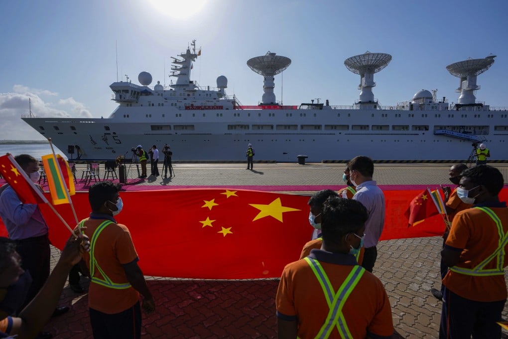 Sri Lankan port workers hold a Chinese national flag as they welcome the Yuan Wang 5 to Hambantota on August 16. Photo: AP