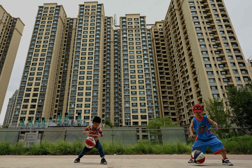 Children play in front of a housing complex by Chinese property developer Evergrande in Beijing on July 28. After years of explosive growth, authorities launched a crackdown on excessive debt in 2020, squeezing financing options for property sector giants such as Evergrande as they struggled to make repayments and restructure mountains of debt. Now they face mortgage boycotts and government pressure to deliver pre-sold homes. Photo: AFP