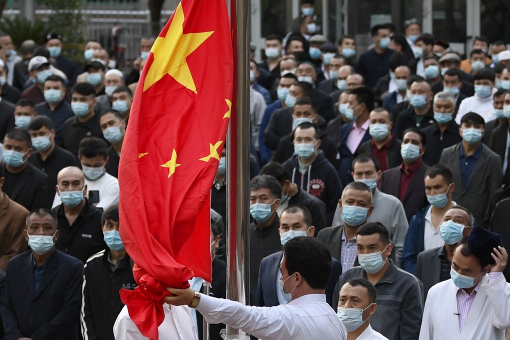 People watching China’s national flag being raised at a mosque in Urumqi in Xinjiang Uygur autonomous region last year. Photo: Kyodo